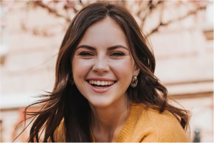 A woman in a yellow sweater smiling