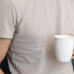 A person in a white t-shirt holding a white cup
