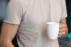 A person in a white t-shirt holding a white cup