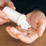 A person pouring white tablets from a white bottle representing Demerol withdrawal symptoms
