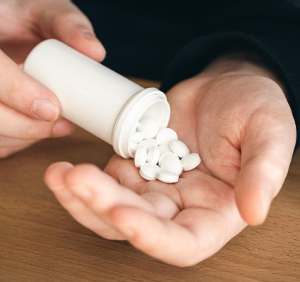 A person pouring white tablets from a white bottle representing Demerol withdrawal symptoms