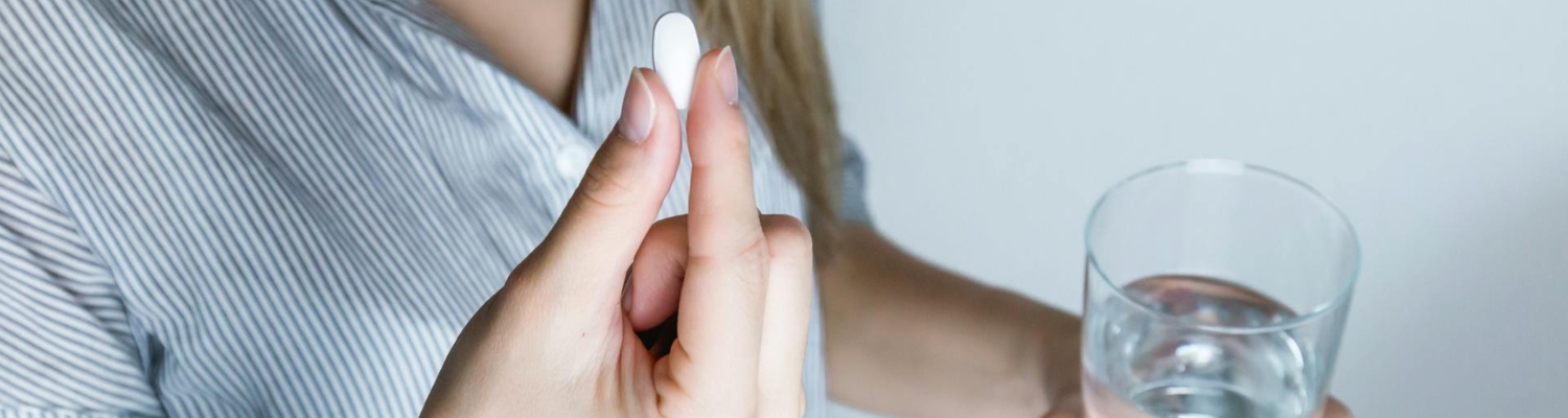 a woman holding a pill and a glass of water