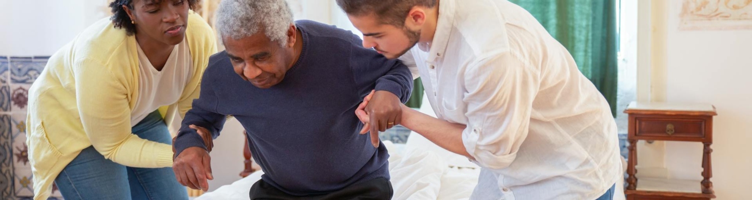 a young man and a woman helping an old man to stand up