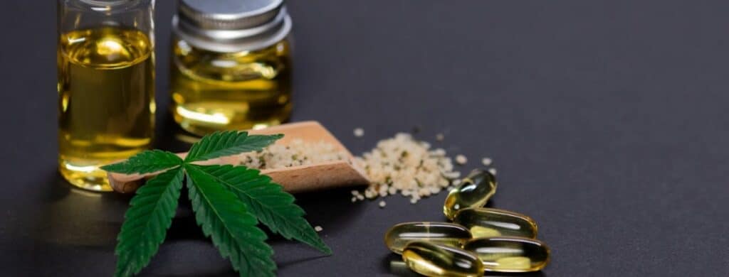 Marijuana leaf, CBD oil and some capsules representing the link between marijuana legalization and addiction
