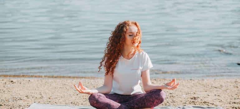 A person doing yoga on the beach, which shows how California's climate helps in substance abuse recovery