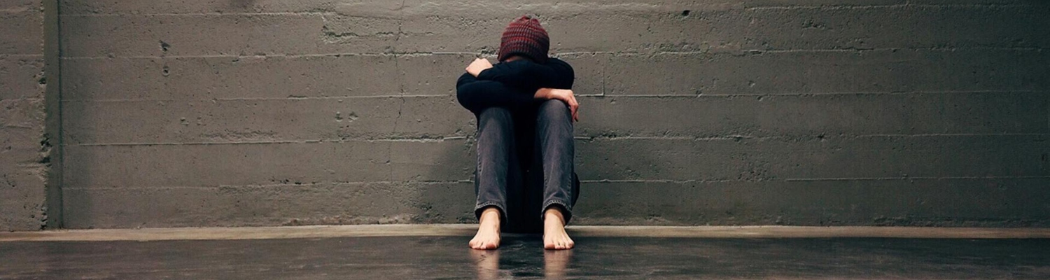 a man sitting on the floor with a head on his knees due to cocaine and depression