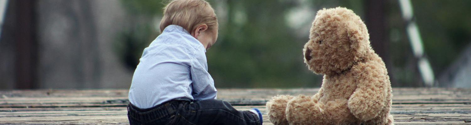 A child alone with a stuffed animal, showing the impact of parental addiction on child development can have social consequences. 