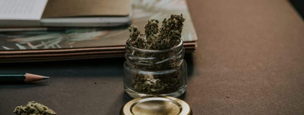 A small jar of marijuana next to some notebooks
