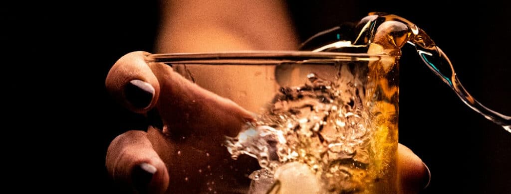 A close up of woman's hands holding a glass filled with an alcoholic beverage